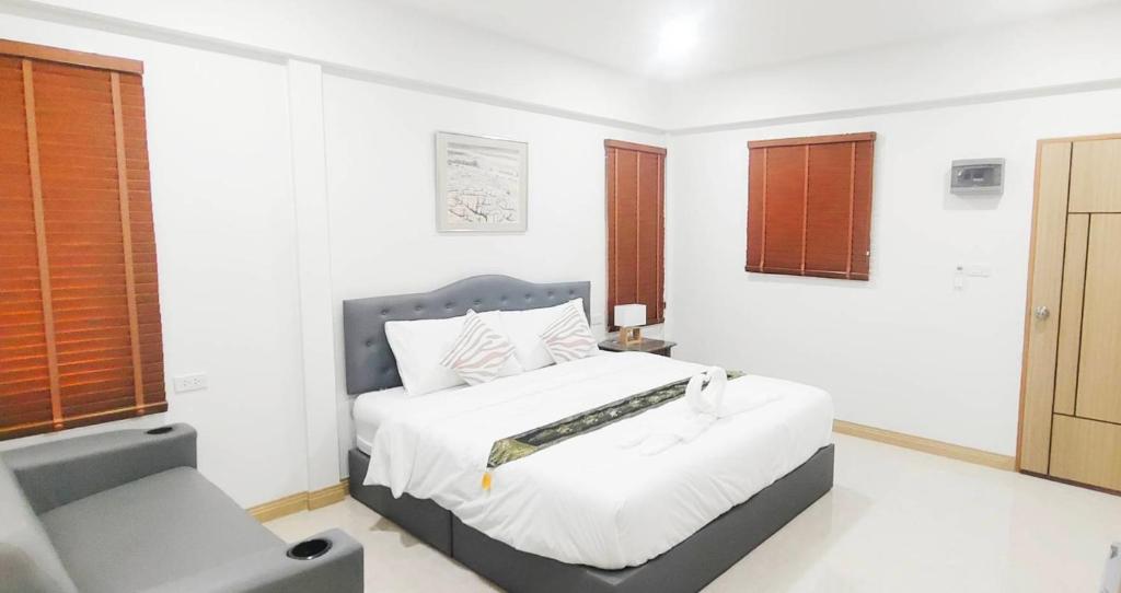 a white bedroom with a bed and a chair at DD Villa in Pathiu