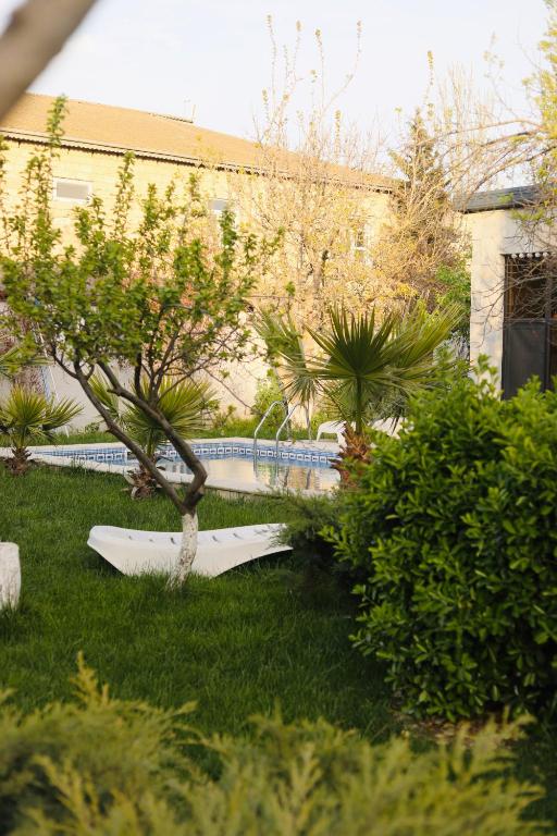 a garden with a tree and a boat in the grass at Villa Verde w Warm Pool, BBQ, Concierge in Baku