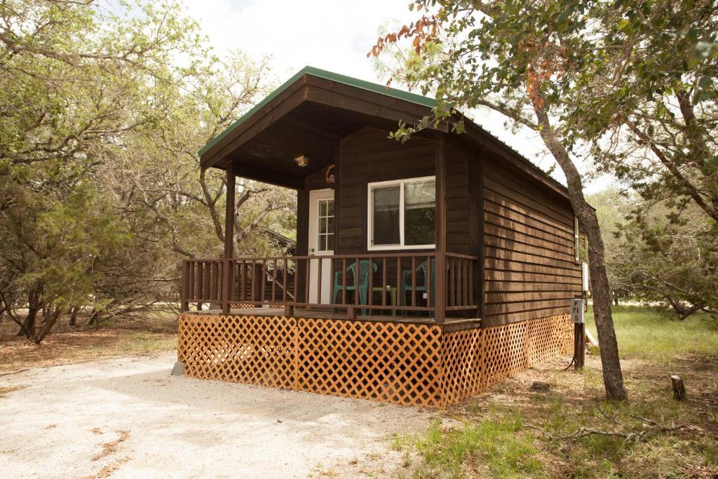 eine kleine Hütte im Wald mit einem Baum in der Unterkunft Medina Lake Camping Resort Studio Cabin 1 in Lakehills