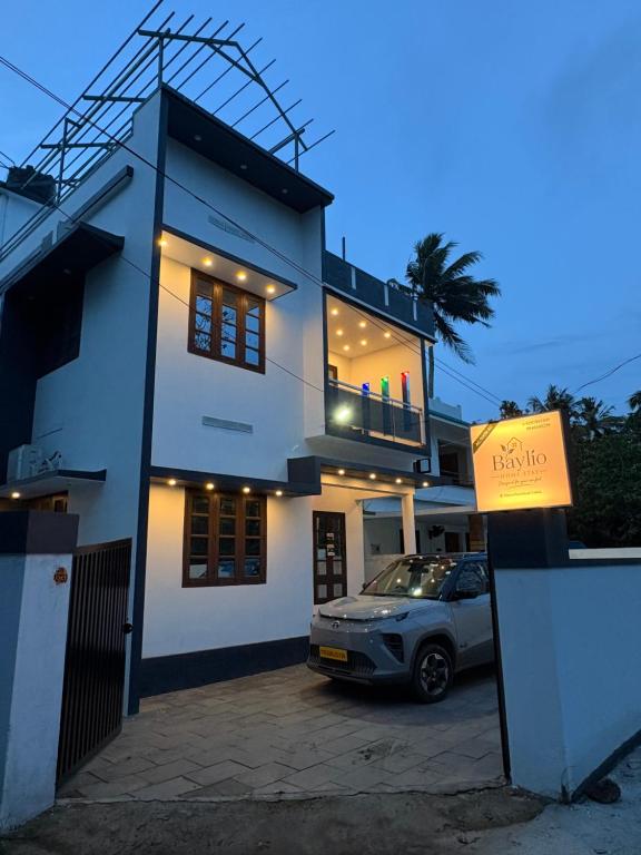 a white house with a car parked in front of it at Baylio Homestay Varkala in Kappil