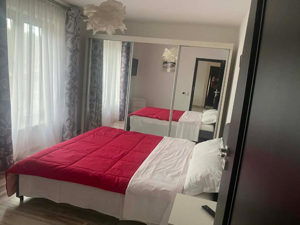 a bedroom with a red bed and a mirror at Mountain Bloom House in Galda de Sus