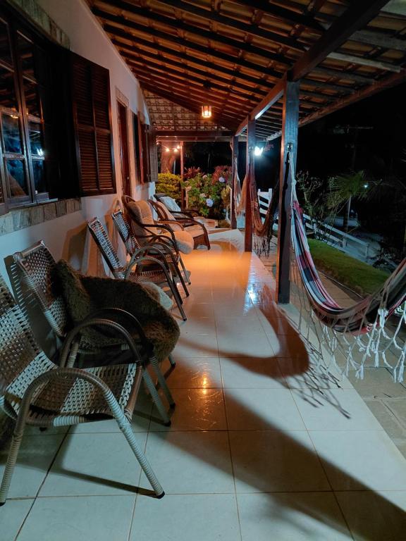 a group of chairs and hammocks on a porch at night at Casa de Campo em Teresópolis in Teresópolis