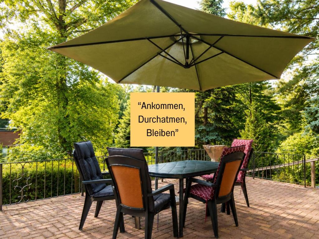 a table and chairs with a green umbrella at Sonnendeck - Familienzeit im Wald in Dahlen