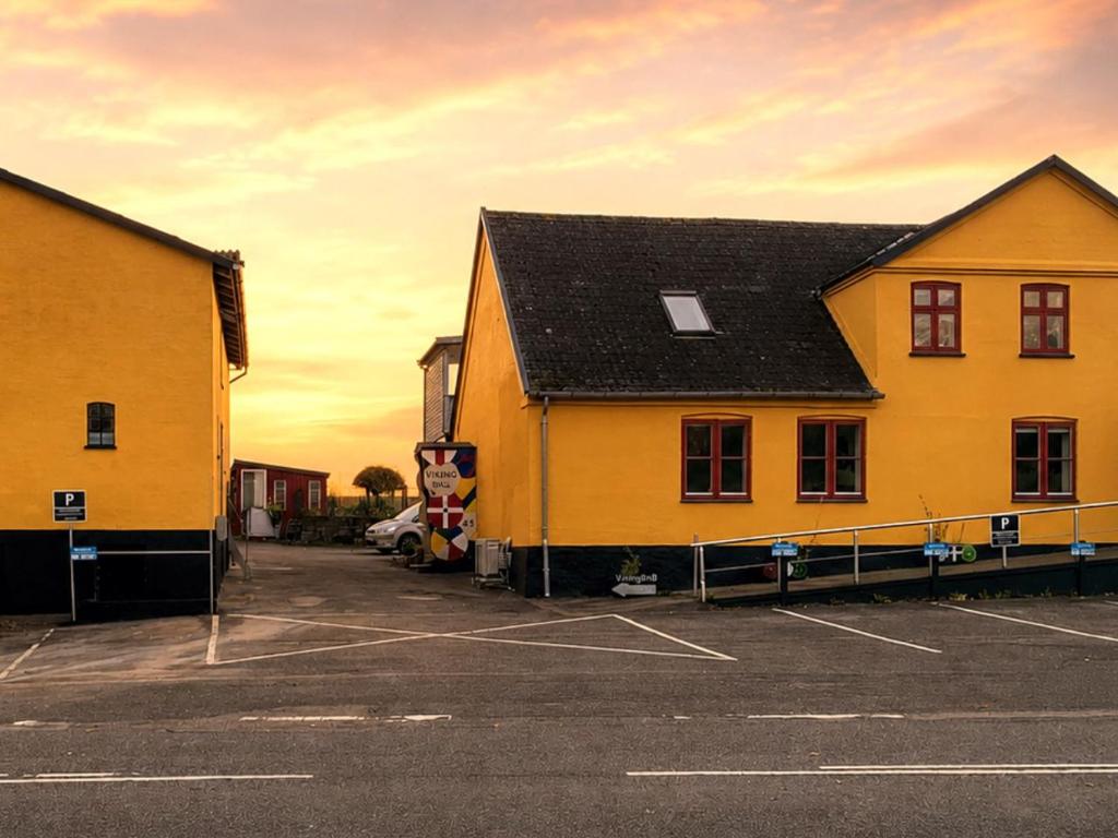 a yellow building in a parking lot next to a building at VikingBnB in Kirke Såby