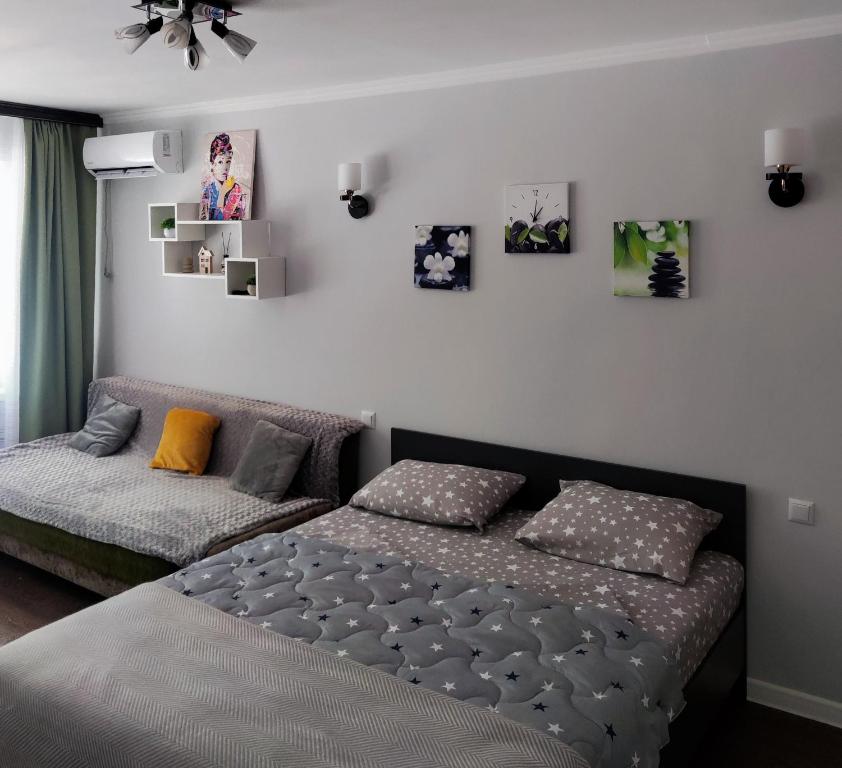 a bedroom with a bed and a couch and pictures on the wall at Сдается квартира у Озера in Balqash