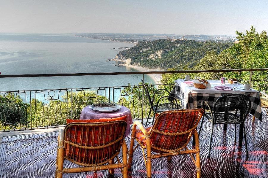 un tavolo e sedie su un balcone con vista sull'oceano di Villa Sibilla a Sirolo