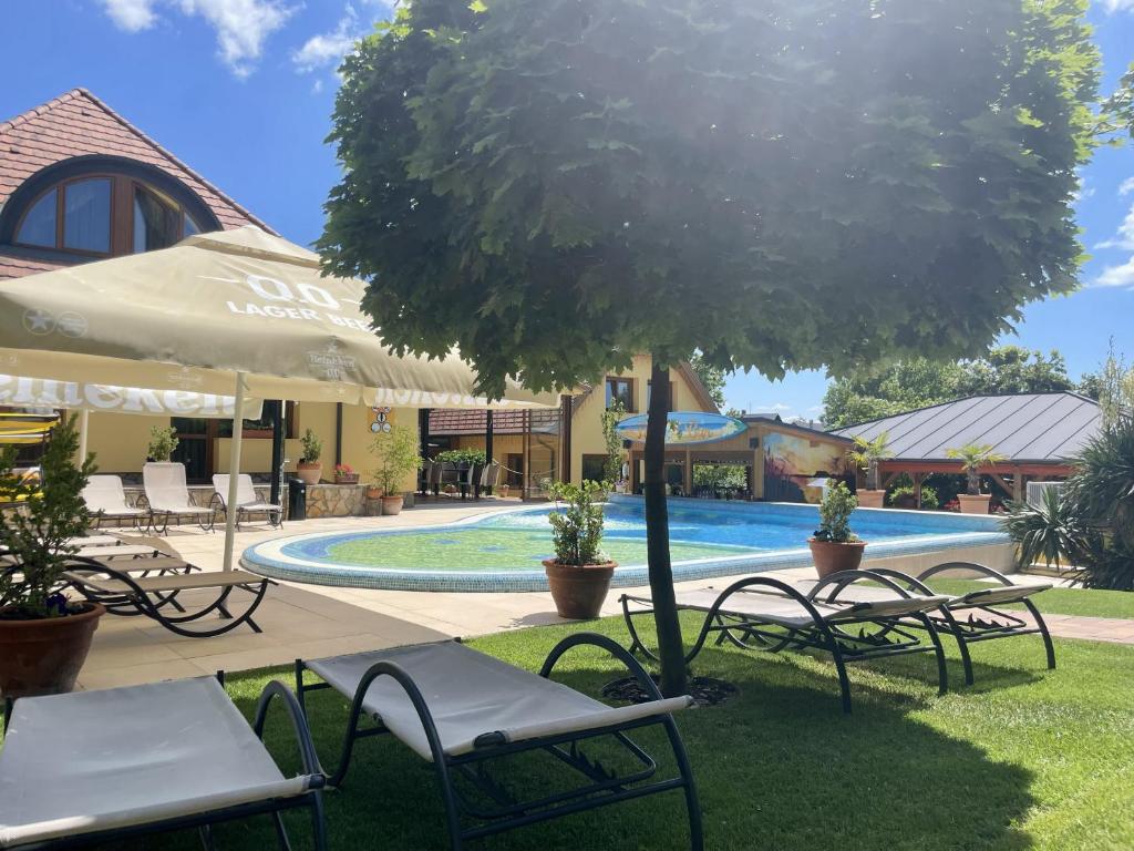 a group of chairs and a tree next to a pool at Hotel Mayer Alsóörs in Alsóörs