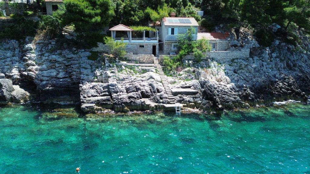 a house sitting on a cliff next to the water at Jube vacation in Žrnovo
