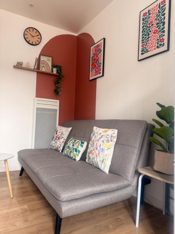 a couch in a living room with a clock on the wall at Escale Confort A1-2 Chambres Stationnement Facile in Roye