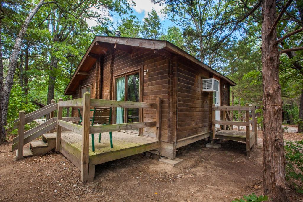 Cabaña de madera en el bosque con porche en Lake Texoma Camping Resort Cabin 17, en Willow Spring