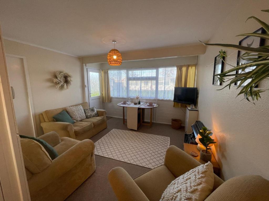 a living room with couches and a table in a room at Beach Chalet Home in Scratby