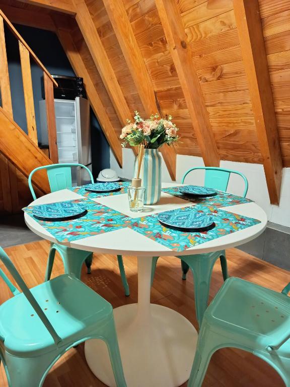 a white table with chairs and a vase with flowers at Cabaña Alpina Los Treiles in Panguipulli