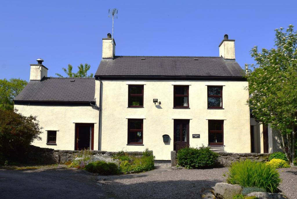 an old white house with a black roof at Hen Gamdda Fawr in Llanallgo