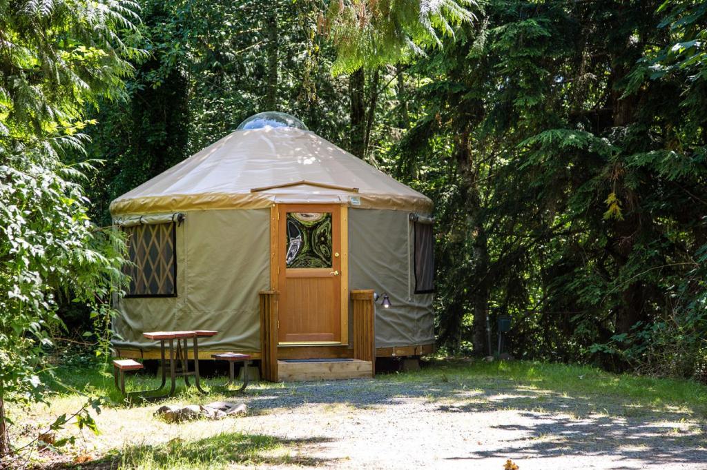 a yurt with a wooden door and a bench at Mount Vernon Camping Resort 16 ft. Yurt 6 in Bow