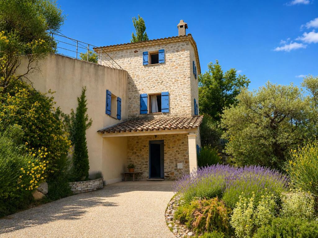 a large stone house with blue windows and a driveway at Le mas des genêts in Nyons
