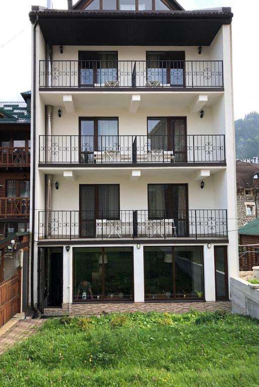 an apartment building with balconies and a yard at Dolyna Gir in Bukovel