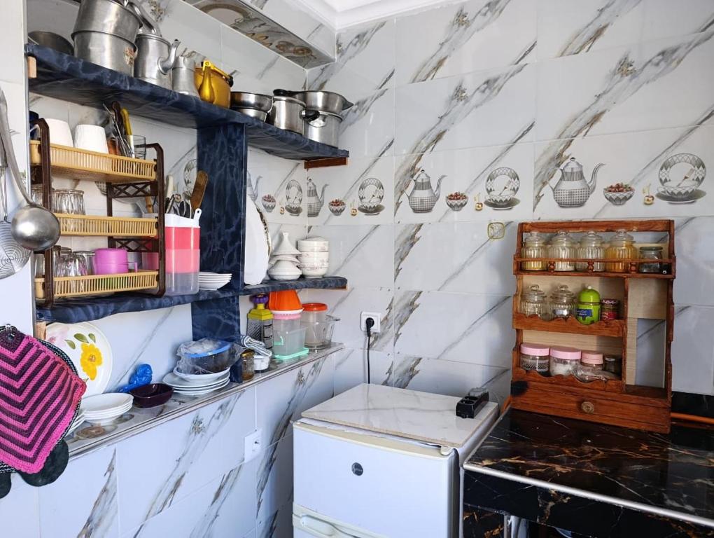 Una cocina con paredes de mármol blanco y un refrigerador. en Ouadlaw, en Oued Laou