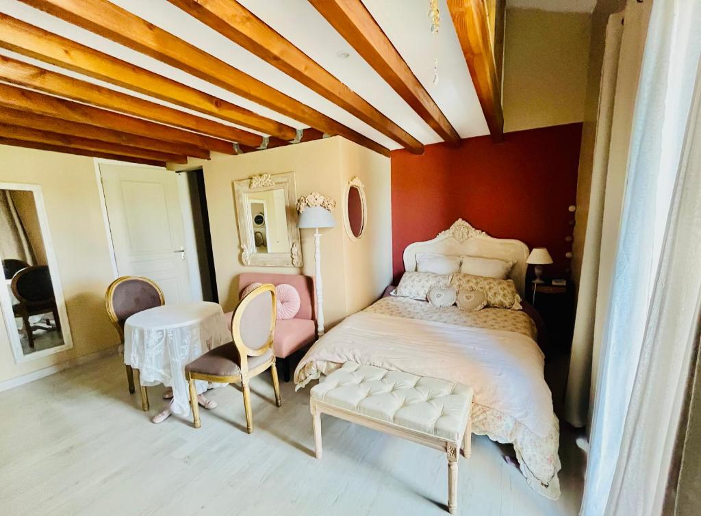 a bedroom with a bed and a table and chairs at Le Boudoir, inclus petit déjeuner in Quincié-en-Beaujolais