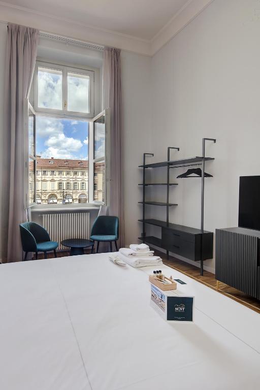 a white room with chairs and a large window at San Carlo Suite Torino in Turin