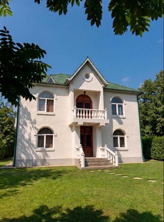 a large white house with a balcony on a lawn at GuestHouse Tekhura in Martvili