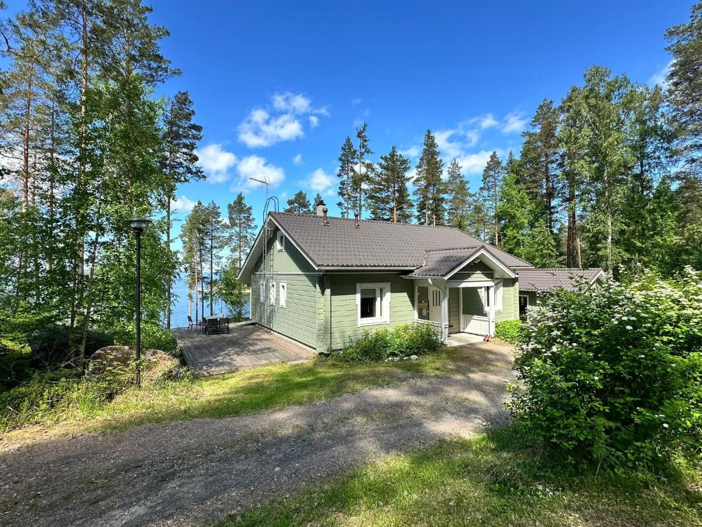 a small green house in the middle of a road at Lake Cottage Onnenranta in Kolinkylä