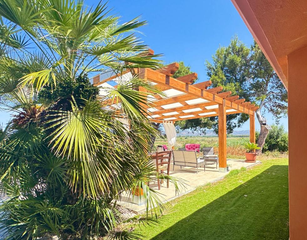 a patio with a wooden pergola and a palm tree at La Nuova Rinascita in San Giovanni Suergiu