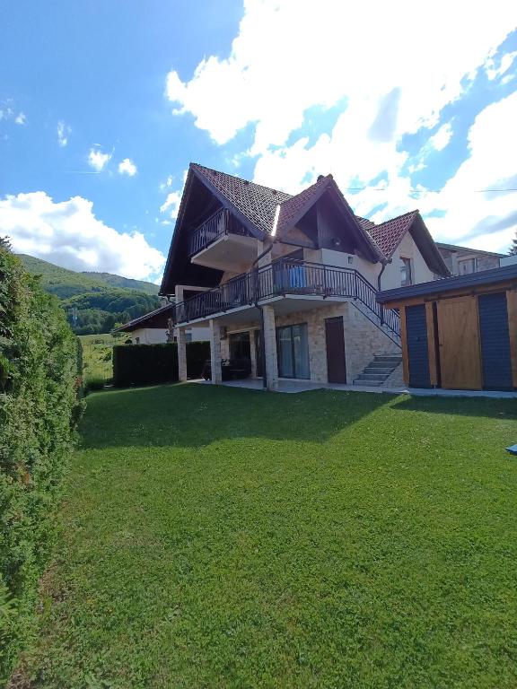 a large house with a grass yard in front of it at Apartman Milekic in Mrkonjić Grad