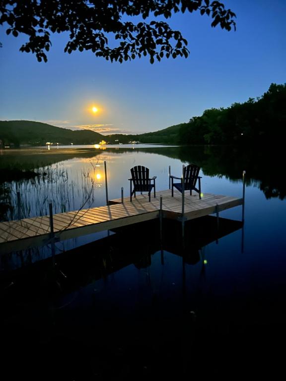 two chairs on a dock on a lake at night at Berkshire Lake Lodge in Becket