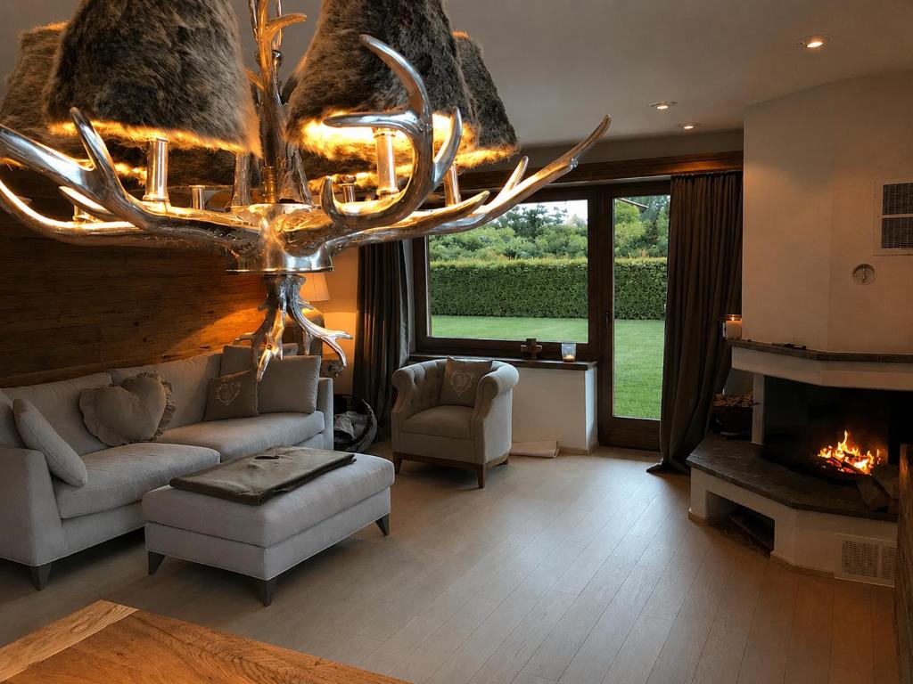 a living room with a fireplace and a chandelier at Genuss in den Bergen! in Klosters Serneus