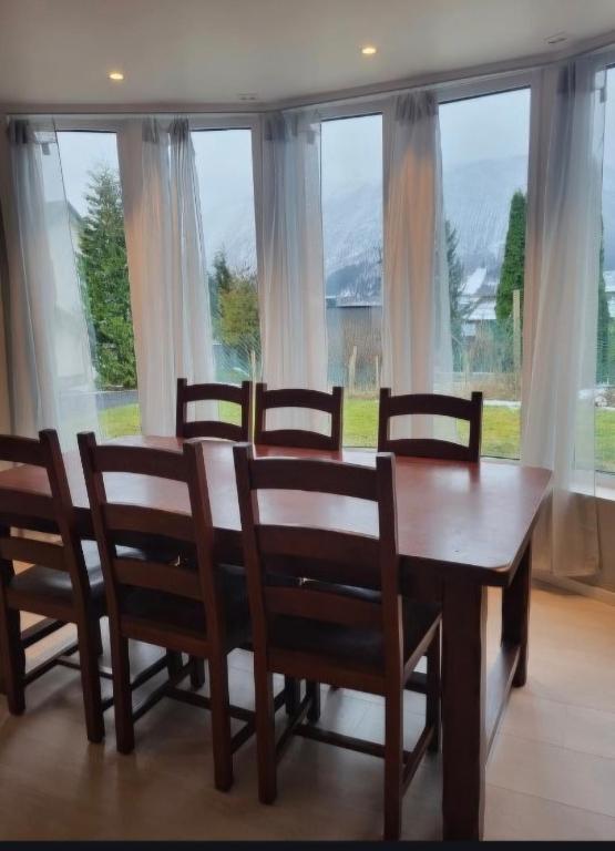 a dining room with a table and chairs and windows at Sentral leilegheit i Ørsta in Ørsta