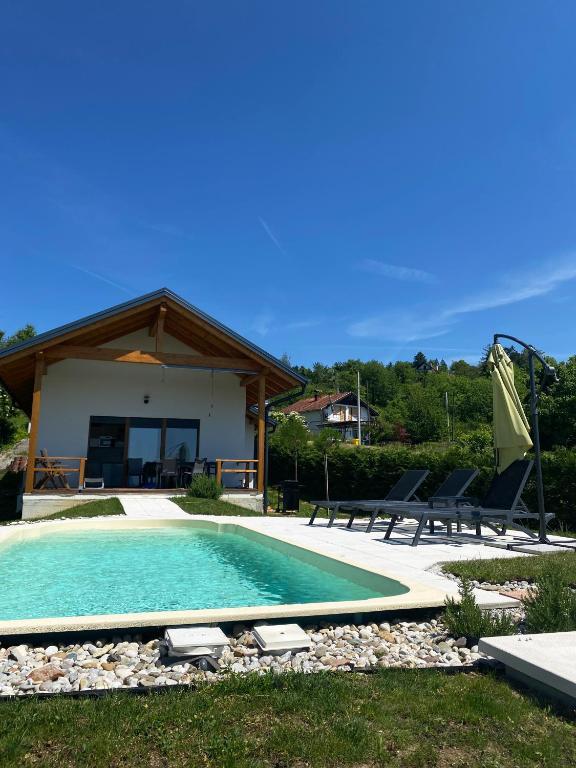 a swimming pool with chairs and a house at Sutla House in Senkovec