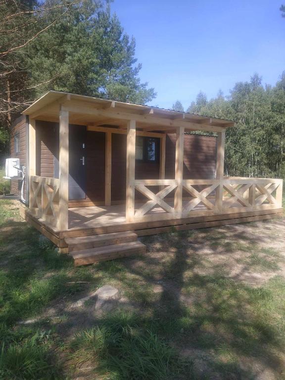 a cabin with a wooden porch in the grass at Powrót do Natury in Orzyny