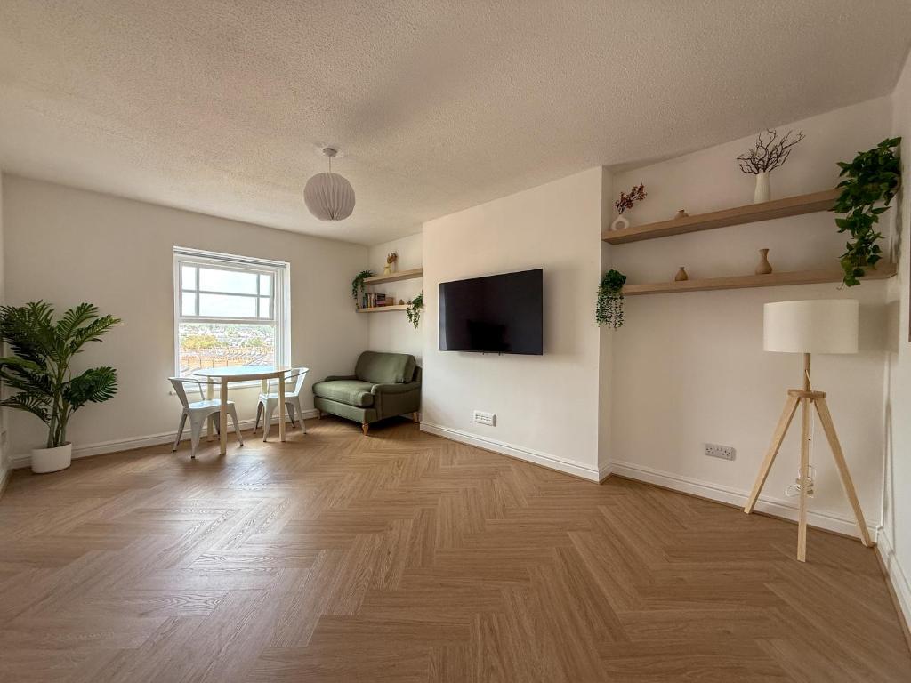 an empty living room with a table and a television at Spacious Central Flat with Parking in Bangor