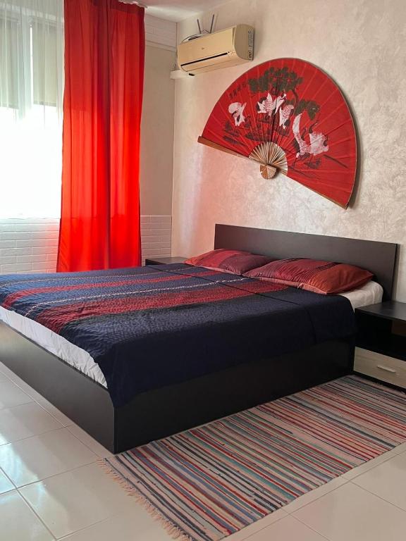 a bedroom with a bed with a red headboard at Helga Apartment in Obzor