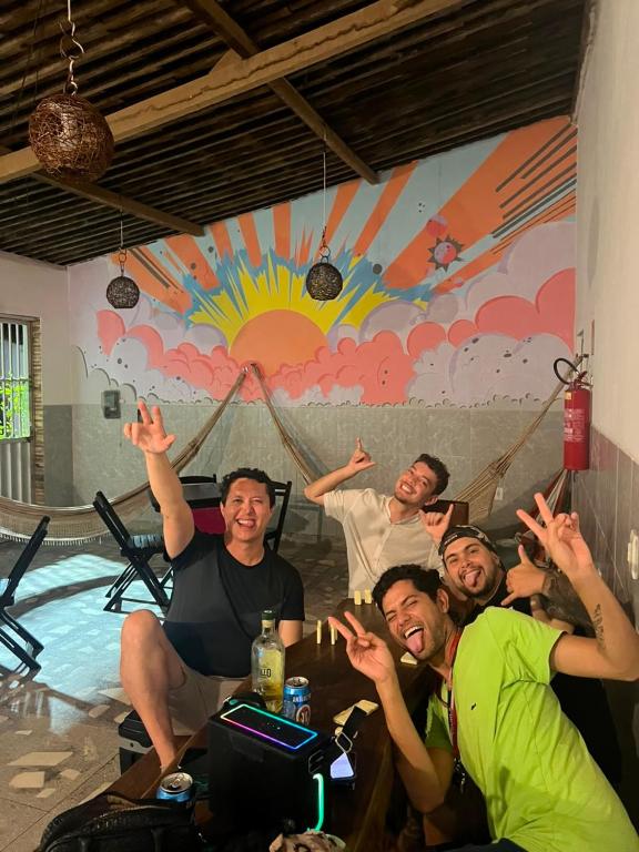 a group of people sitting around a table with their hands up at La Palma Hostel & Bar in Maragogi