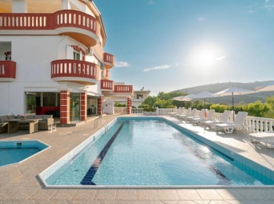 a hotel with a swimming pool in front of a building at Hotel Alexandros in Ammoudia