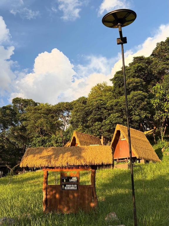 a grass roofed hut in a field with a street light at Abot Langit Calatagan in Calatagan
