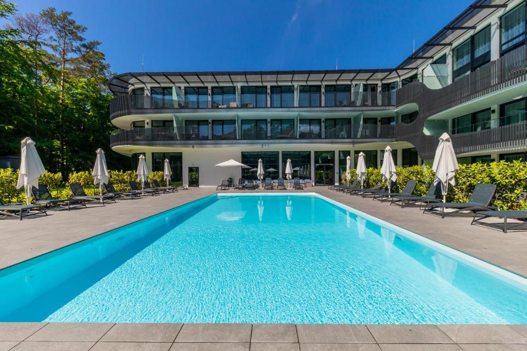 a pool in front of a building with chairs and umbrellas at Apartament Bursztynowa Komnata 116 Stegna nad morzem in Stegna
