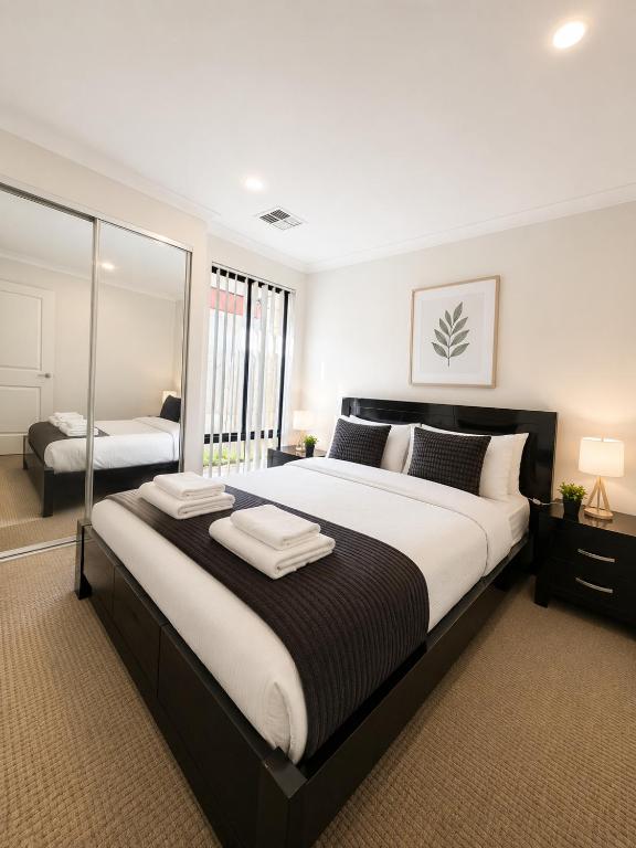 a bedroom with a large bed and a mirror at Modern oasis in Perth