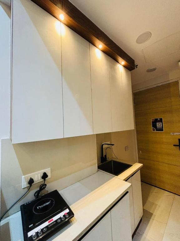 a small kitchen with white cabinets and a sink at THE MOONLIGHT STUDIo in Ghaziabad