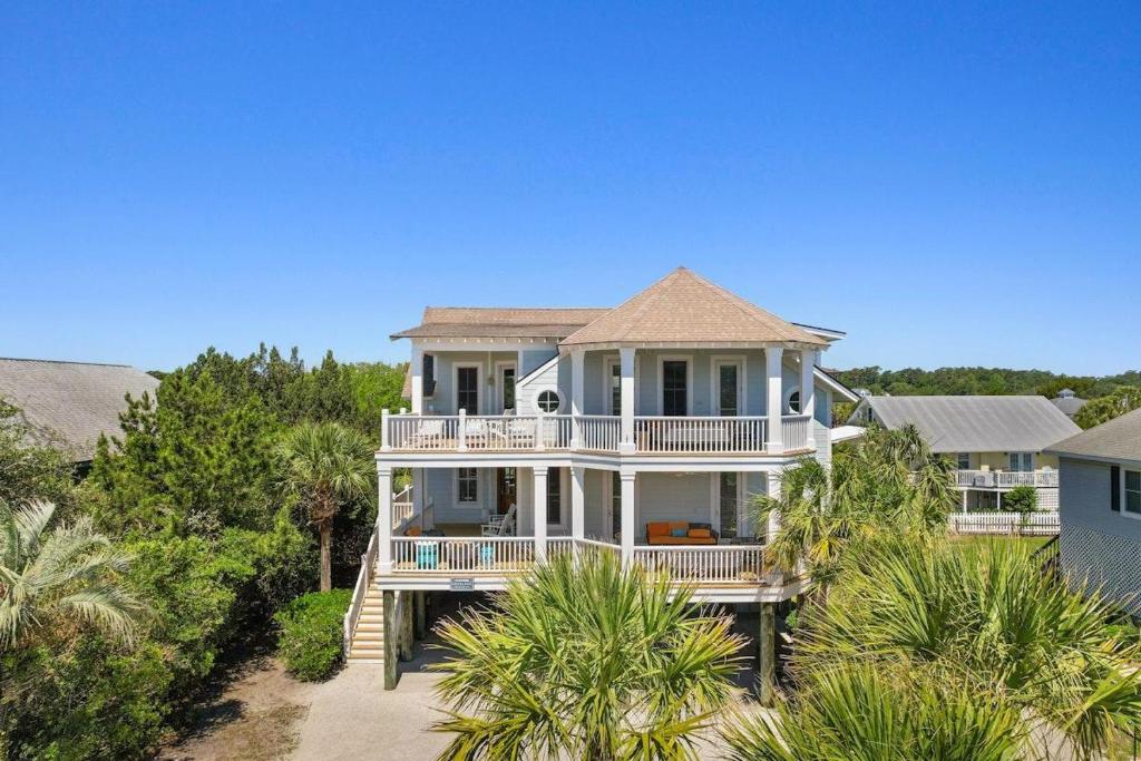 a large white house on the beach with palm trees at Elegant Beachfront Escape with Wrap-Around Porches in Pawleys Island