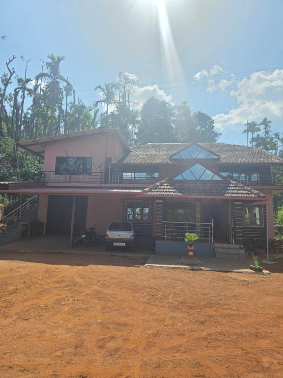 a house with a car parked in front of it at Kaarmugilu Homestay in Kalasa