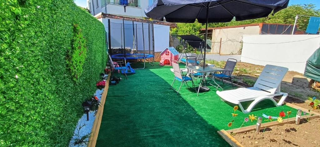 a backyard with a green lawn and chairs and an umbrella at Lux Maisonette in Chernomorets