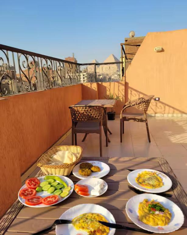 a table with plates of food on a balcony at Pyramids Road Guest House in Cairo