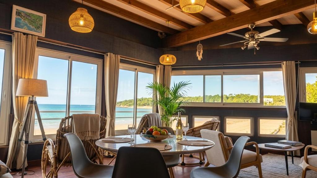 a dining room with a table and chairs and the ocean at Beach apartment - Ocean sunset full view in Meschers-sur-Gironde