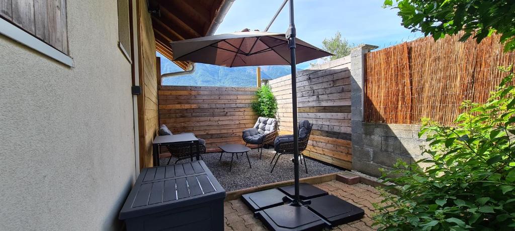 a patio with a table and an umbrella and chairs at Apartment type f1 to in Sainte-Hélène-sur-Isère