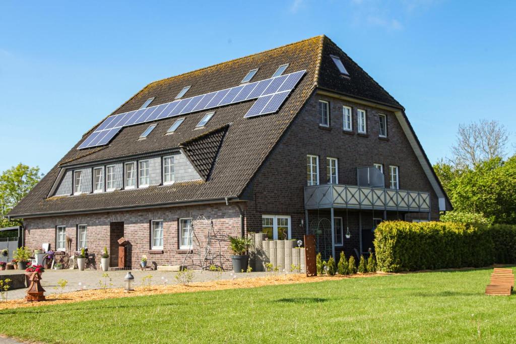 a large house with solar panels on the roof at Ferien- und Pferdehof Egelkraut "Feriendomizil am Meer" in Wangerland