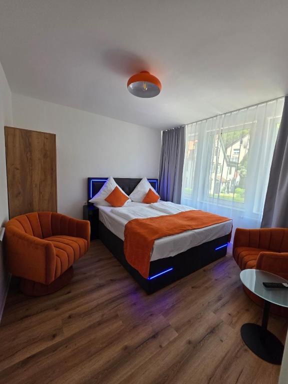 a bedroom with a bed and two orange chairs at Cozy downtown studio in Schwäbisch Hall