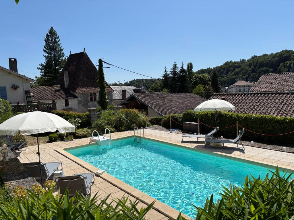 a swimming pool with chairs and umbrellas in a yard at 9 Impasse Saint Martin in Brantôme
