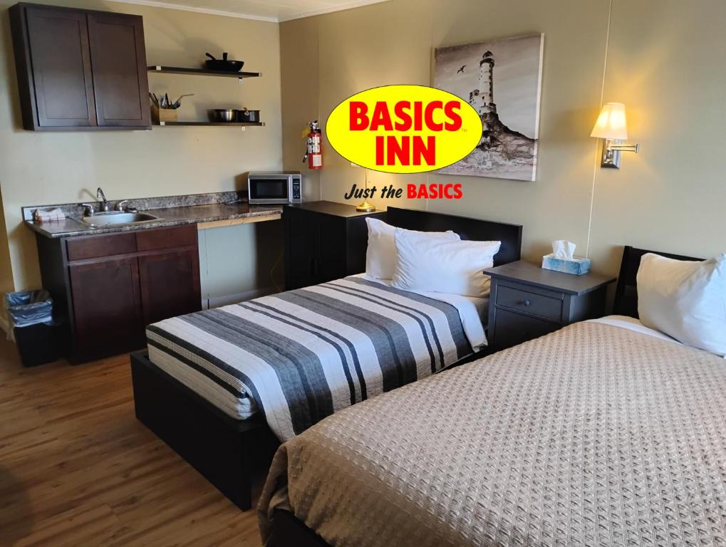 two beds in a hotel room with a sign that reads basics inn just the buses at BASICS Inn in Truro